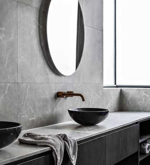 Modern custom bathroom vanity with black vessel basins, dark cabinetry and stone benchtop