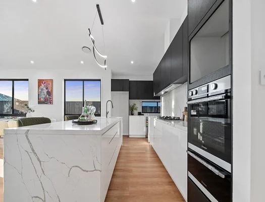Modern kitchen with marble-look waterfall island bench, black cabinetry, built-in wall oven and timber flooring