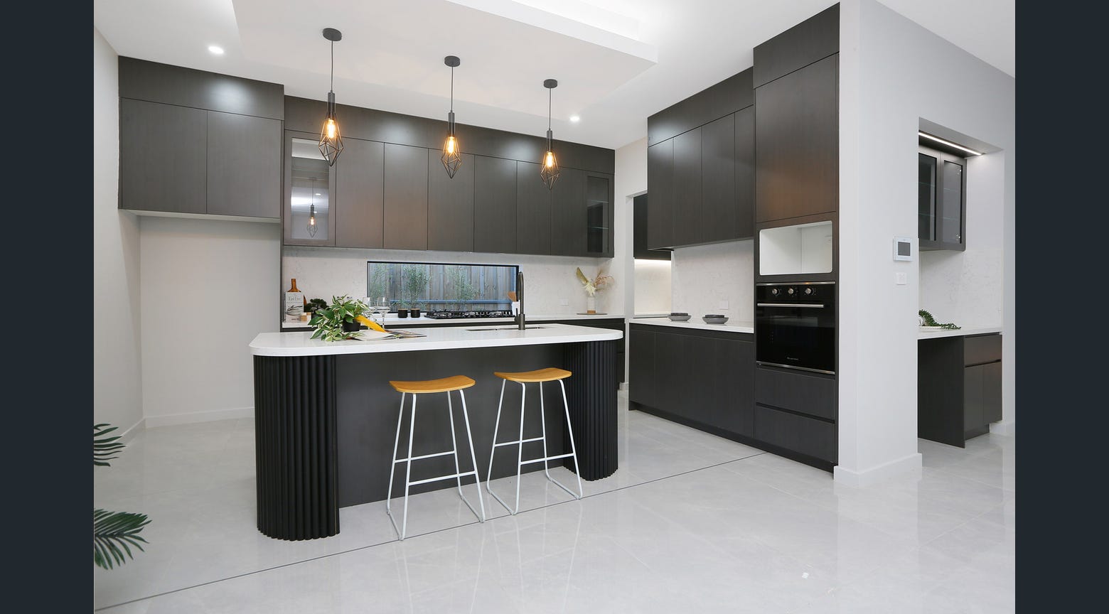 Modern black custom kitchen with fluted island, white benchtop and timber bar stools