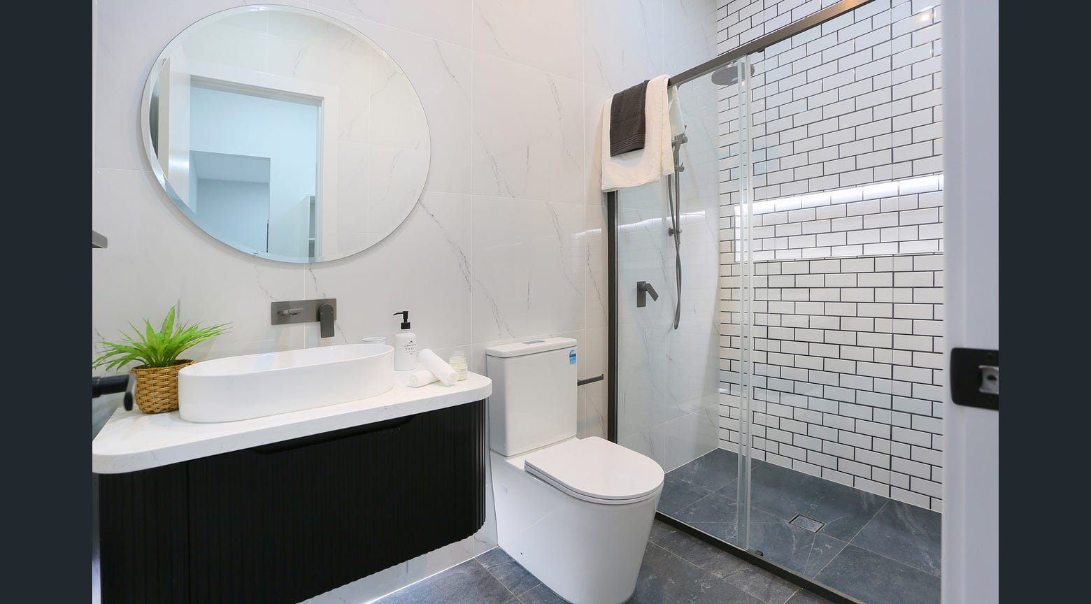Modern bathroom with black fluted vanity, white stone benchtop and glass shower enclosure