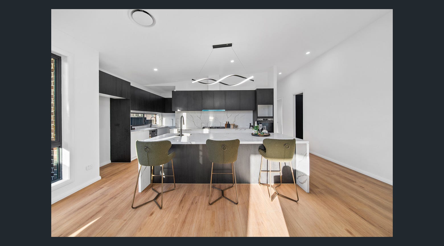 Contemporary black and white custom kitchen with large stone island and breakfast stools
