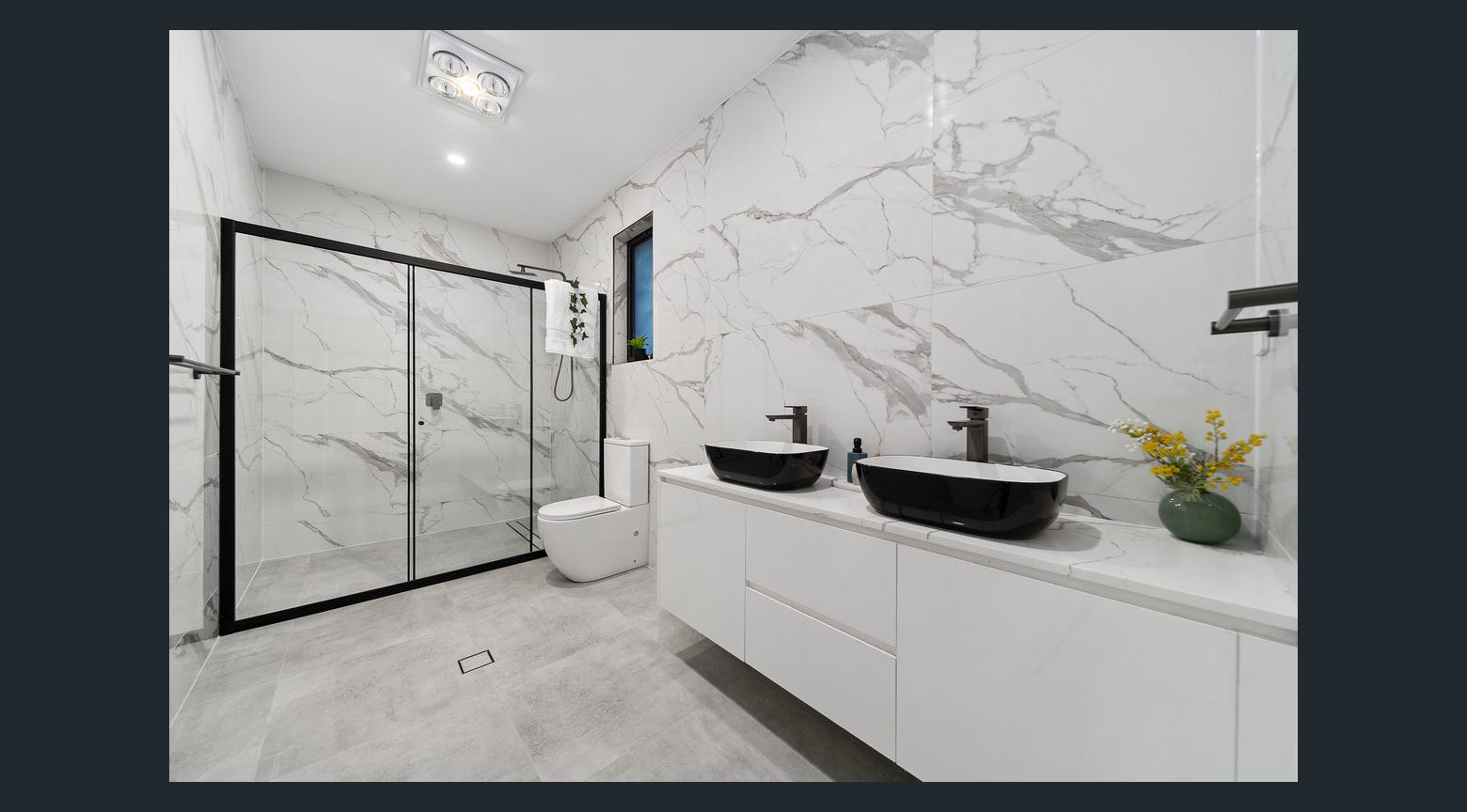 Luxury double vanity bathroom with black vessel sinks, white custom cabinetry and marble-look walls
