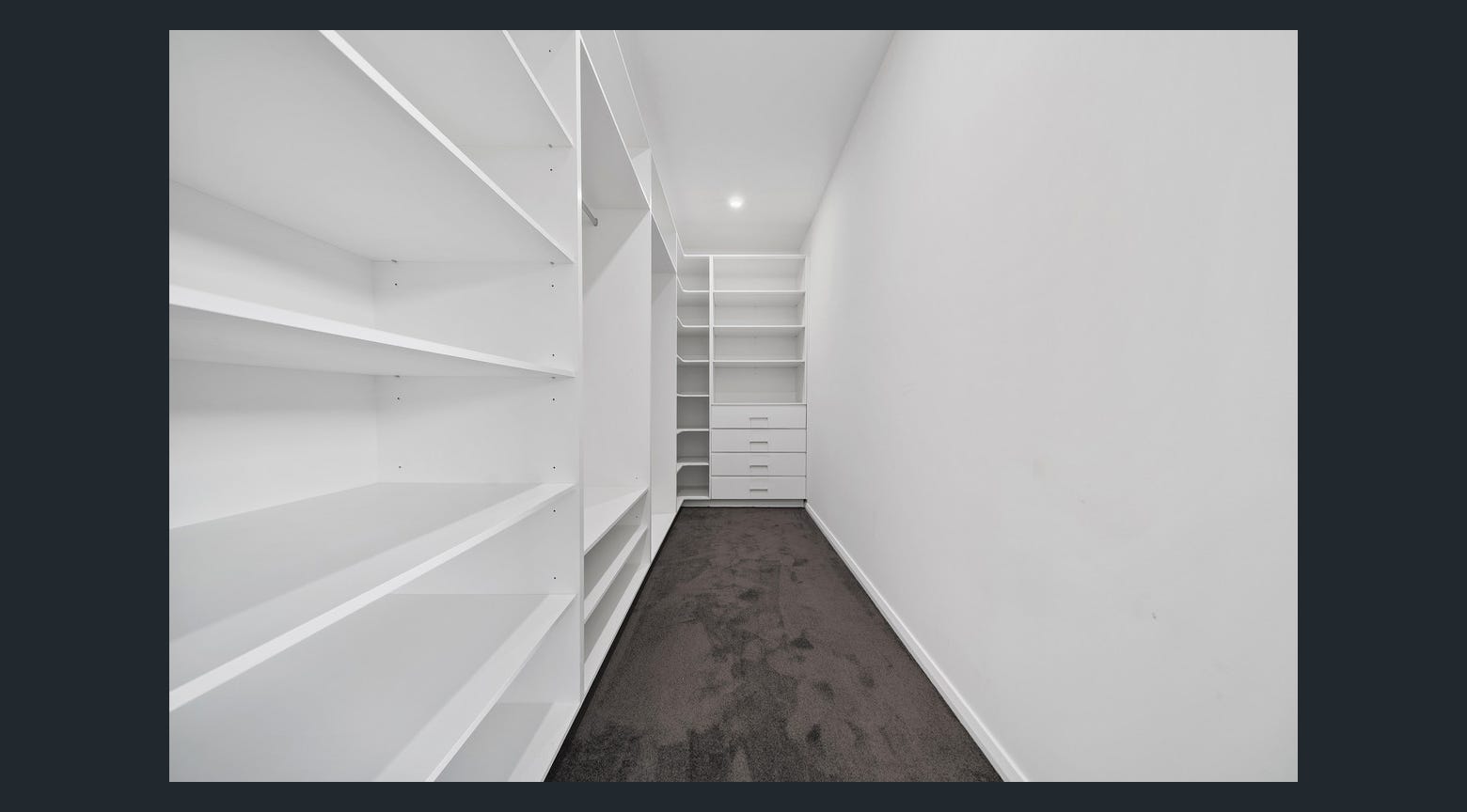 Custom white walk-in wardrobe with built-in shelving, drawers and carpeted flooring
