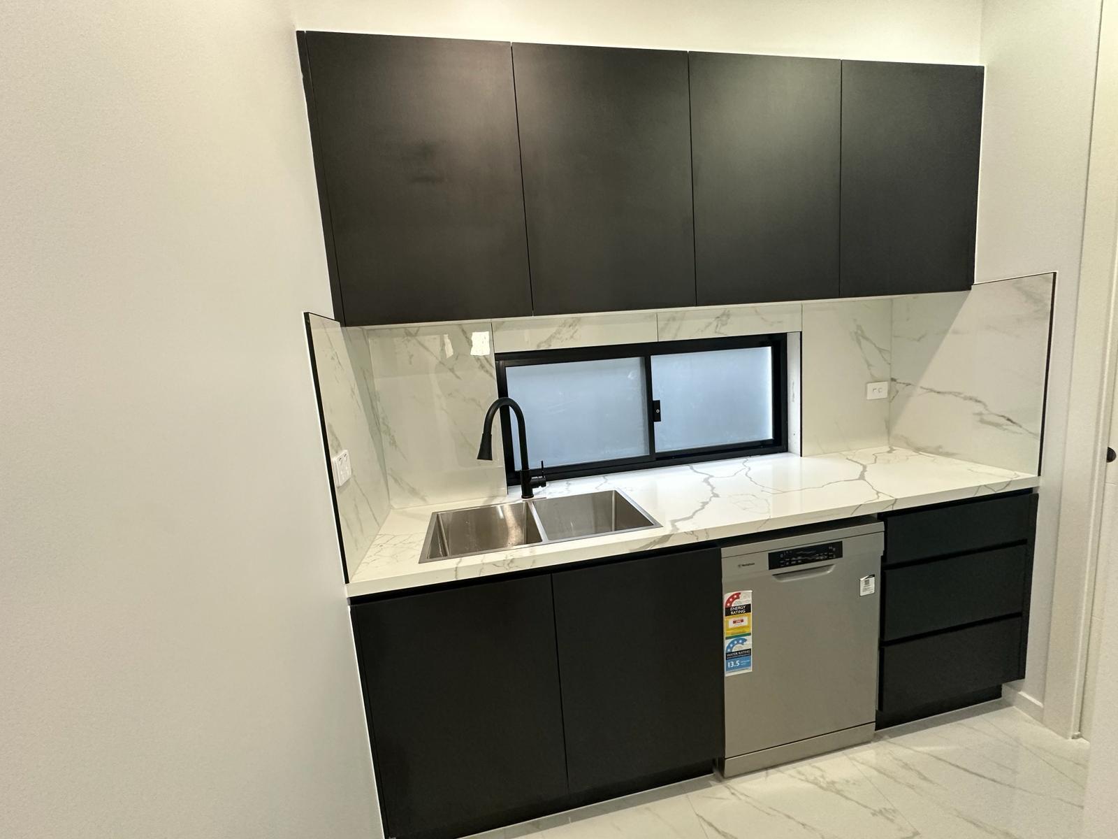 Custom black kitchen cabinetry with marble benchtop, double sink and integrated dishwasher