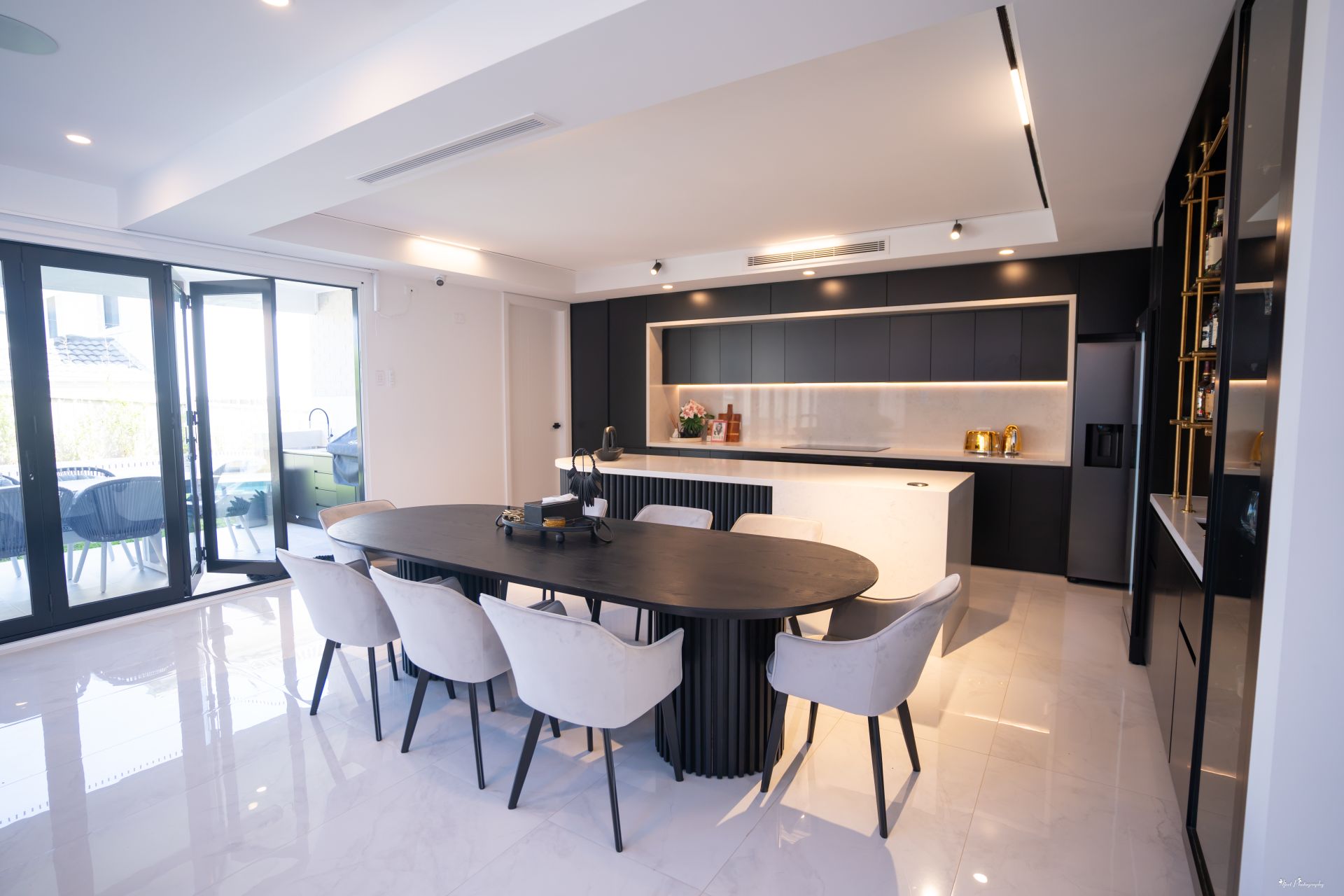 Modern custom kitchen and dining area with black cabinetry, white island and large dining table