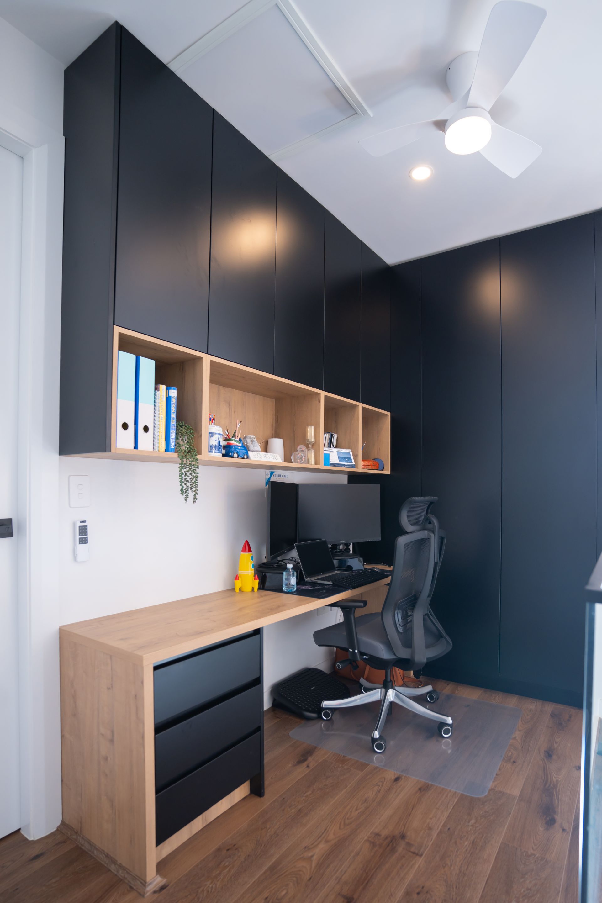 Custom home office joinery with black built-in cabinets, timber desk and open shelving