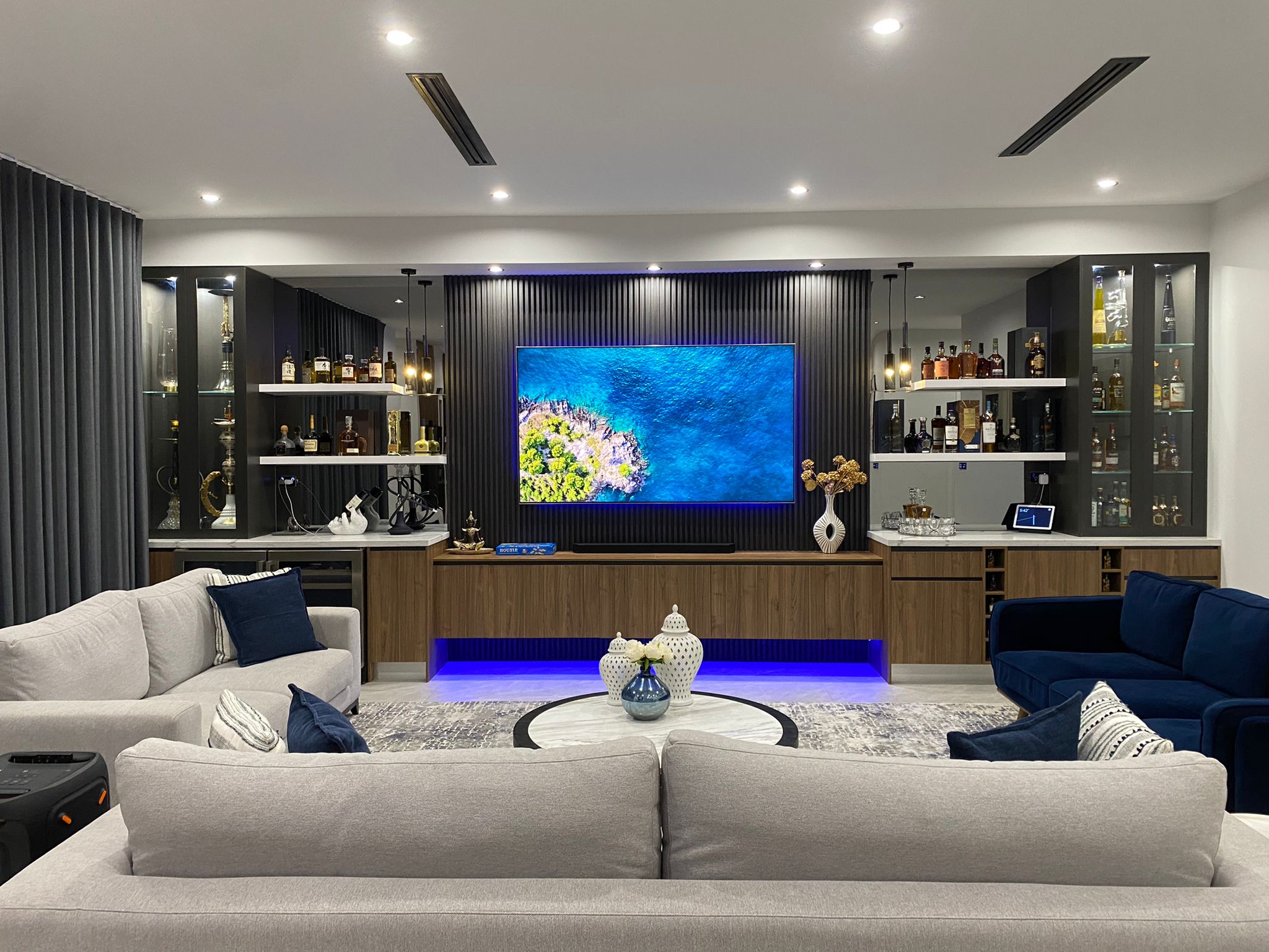 Custom living room entertainment unit with built-in bar cabinets, display shelving and wall-mounted TV