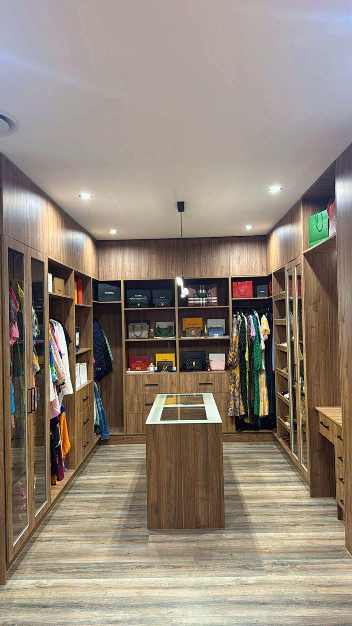 Custom timber walk-in wardrobe with glass display cabinets, clothing storage and central island