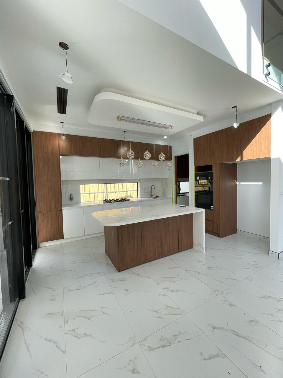 Bright modern kitchen with timber cabinetry, white marble-look island, built-in appliances and pendant lighting