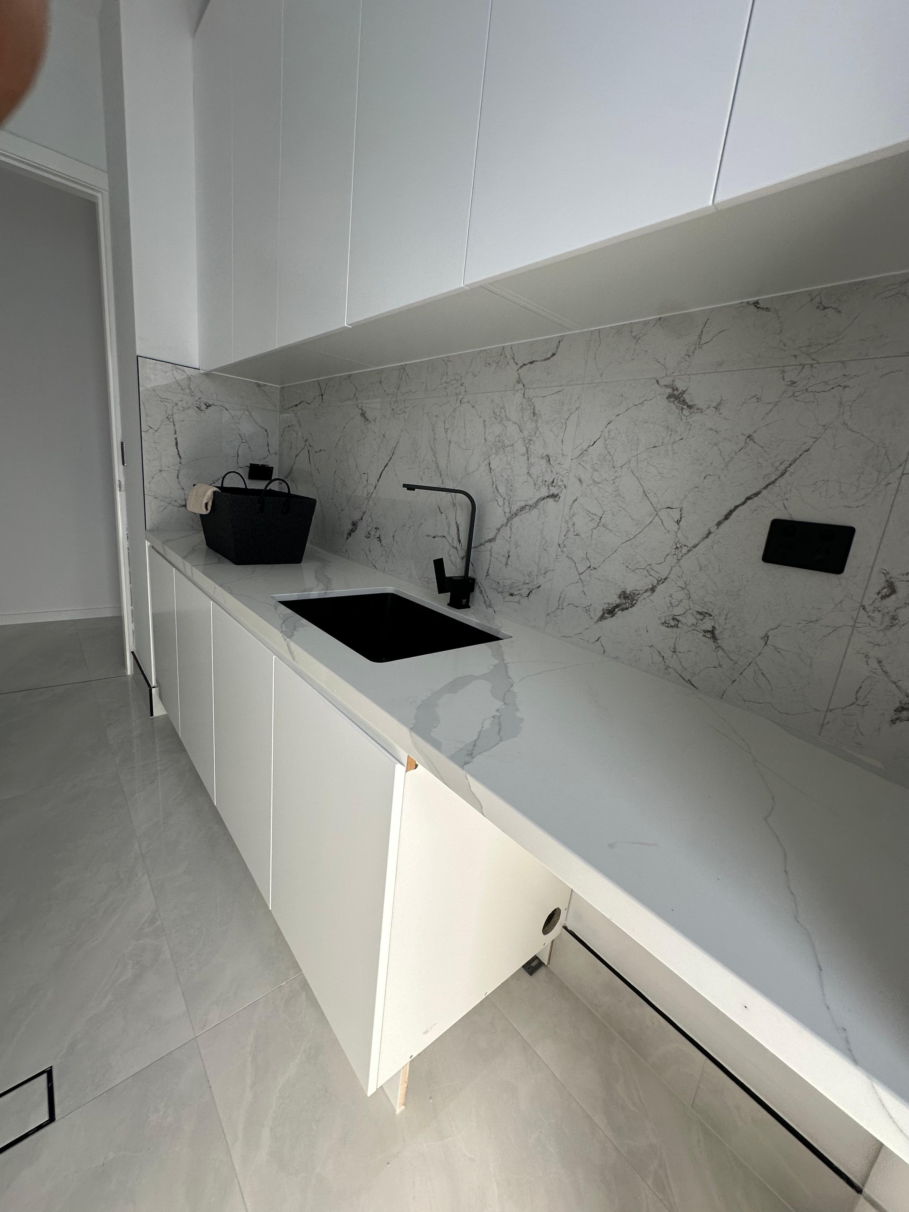 Custom white kitchen cabinetry with marble benchtop, marble splashback, black sink and black tapware