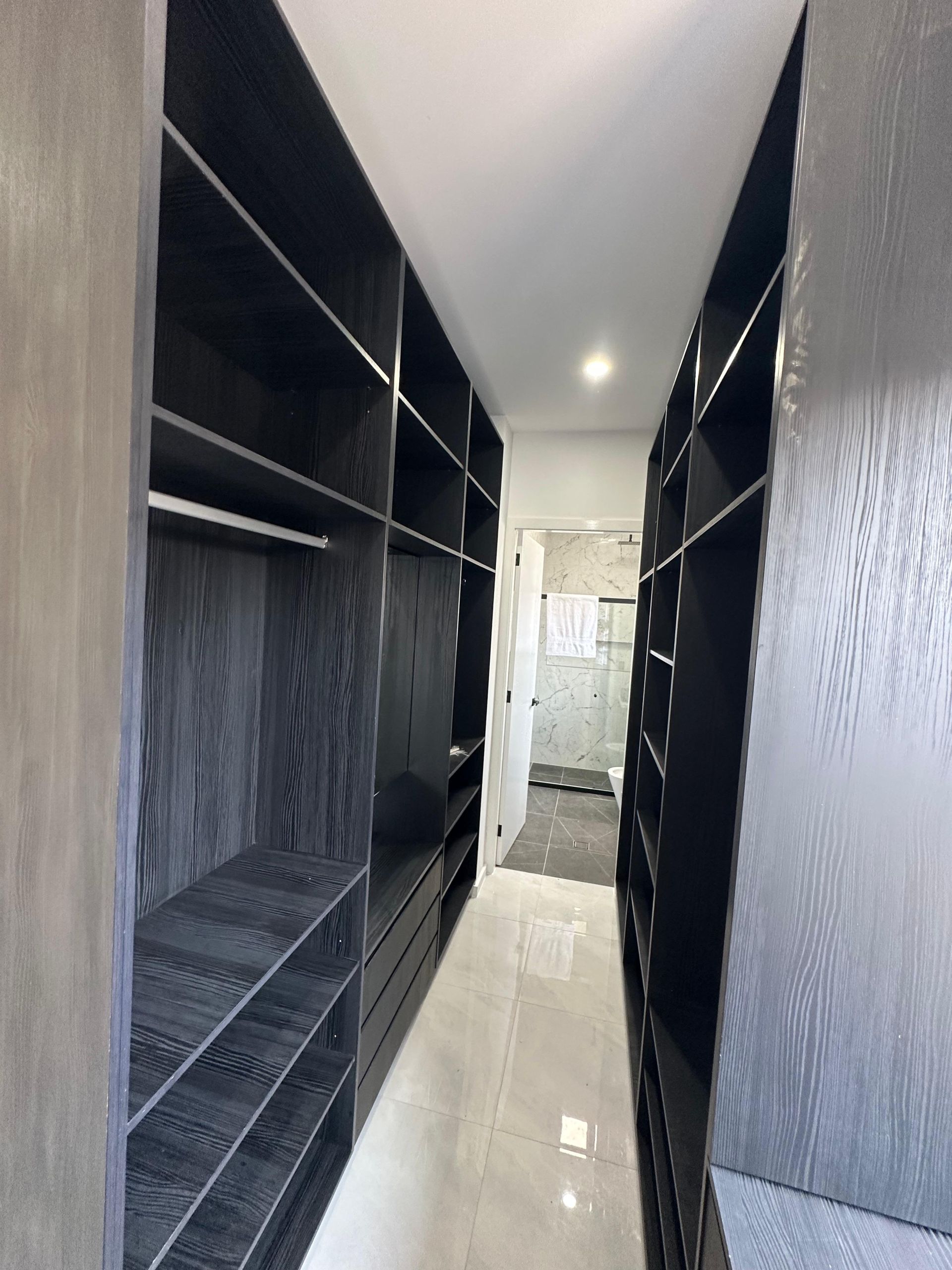 Custom black walk-in wardrobe with open shelving, drawers and built-in storage