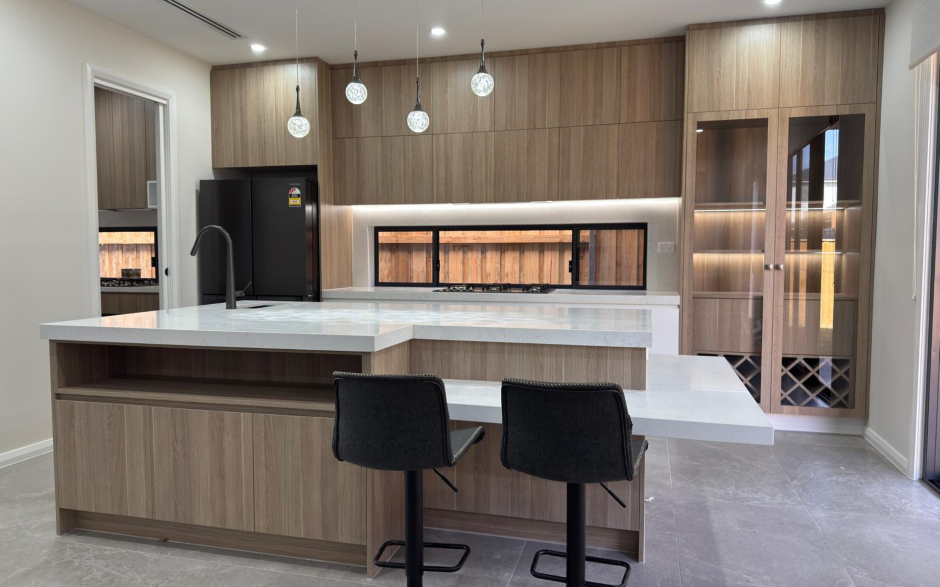 Contemporary kitchen with wood-grain cabinets, white quartz countertops, black appliances and large island