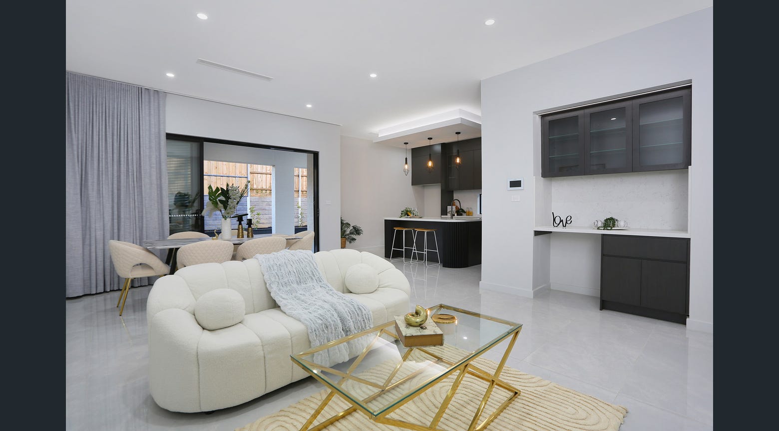 Modern living room with custom dark built-in cabinetry and open-plan kitchen