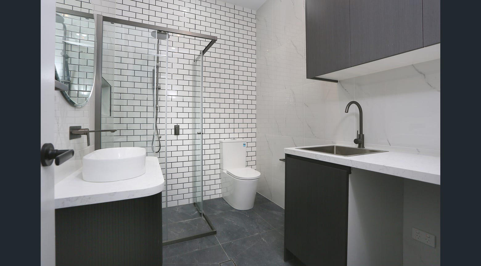 Compact modern bathroom with custom black vanity, white stone benchtop and shower enclosure