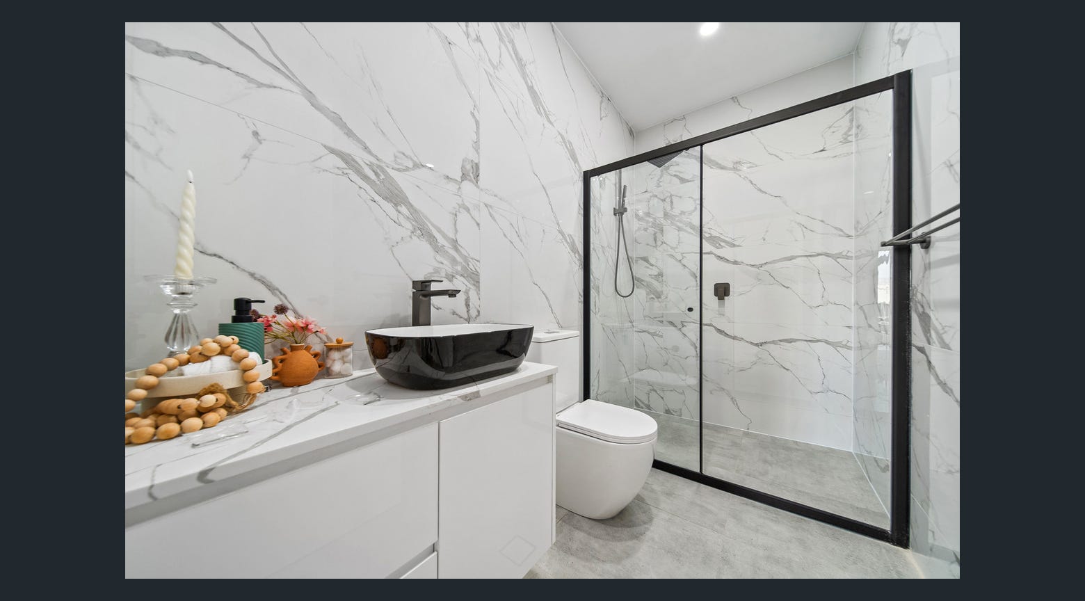 Modern bathroom with black vessel sink, custom white vanity and black-framed shower screen