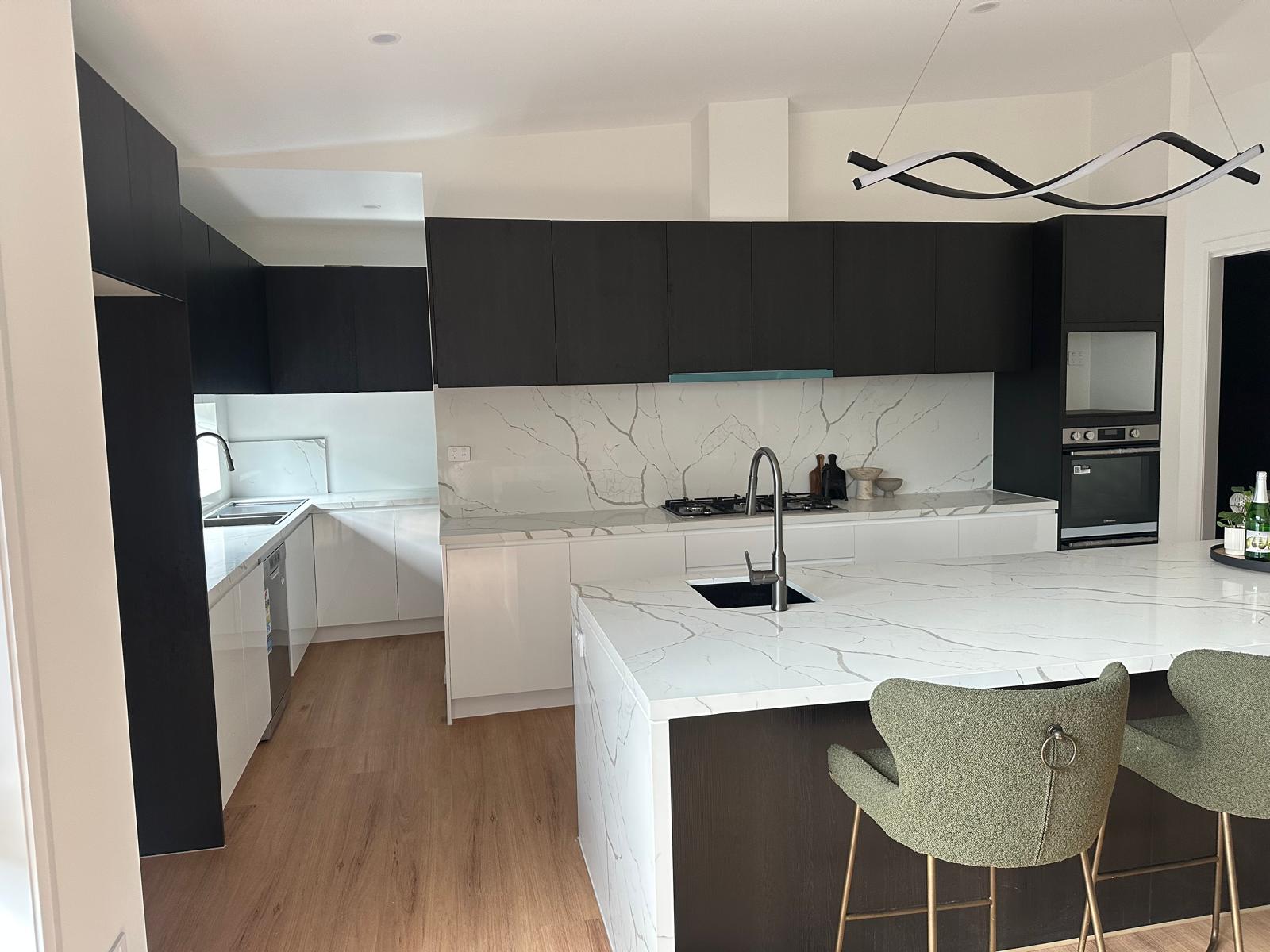 Luxury custom kitchen with dark cabinetry, white marble island and integrated appliances