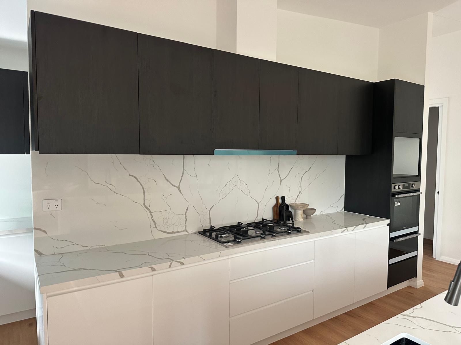 Modern kitchen with black upper cabinetry, white cabinetry and marble-look stone benchtops