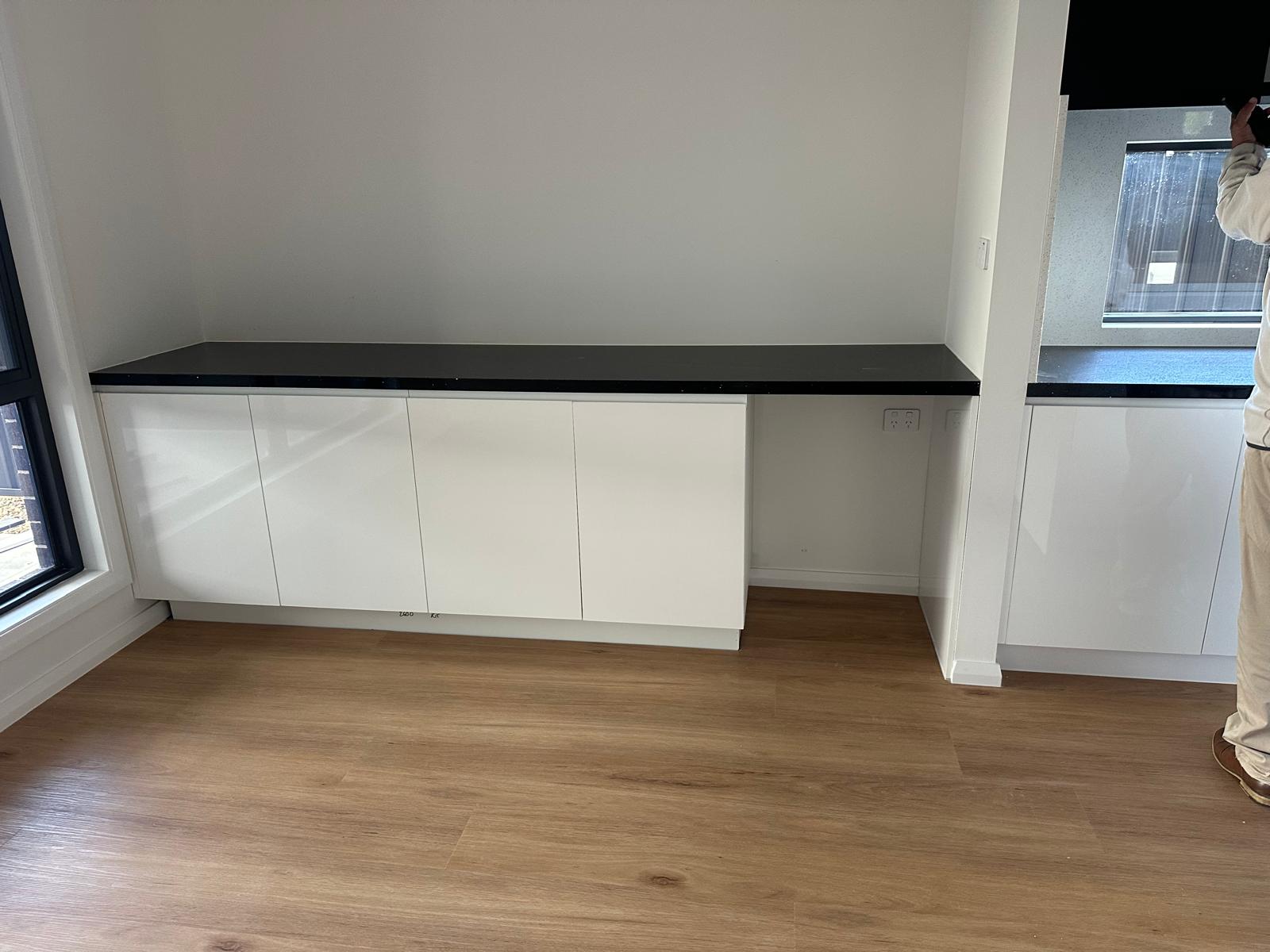 Custom white built-in cabinetry with a black benchtop and open workspace