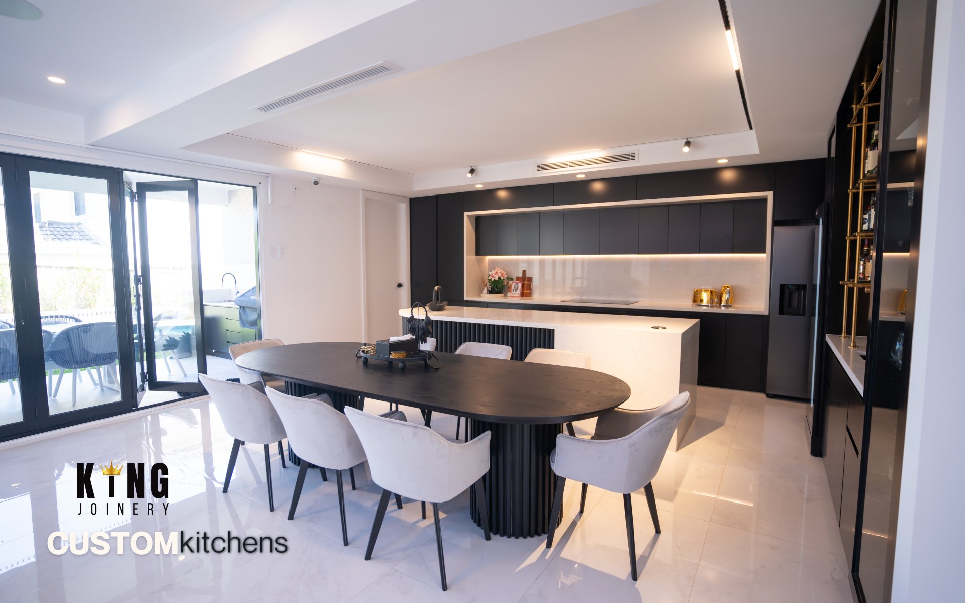 Custom modern kitchen with black cabinetry, white island and dark dining table