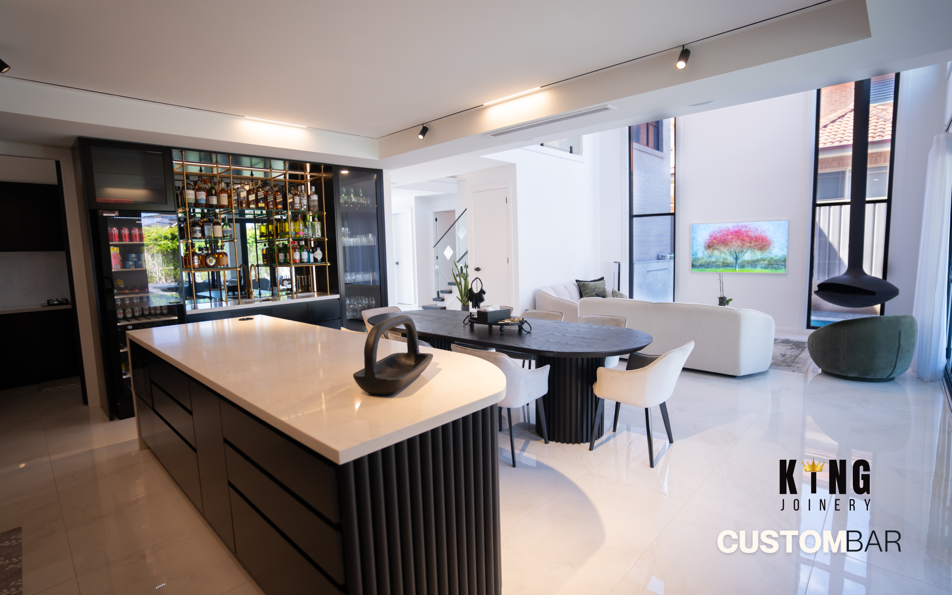 Custom black kitchen cabinetry with white stone island, dining table and built-in bar cabinetry