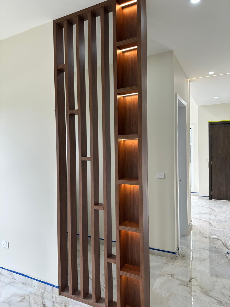 Custom timber room divider with vertical slats and illuminated built-in display shelves
