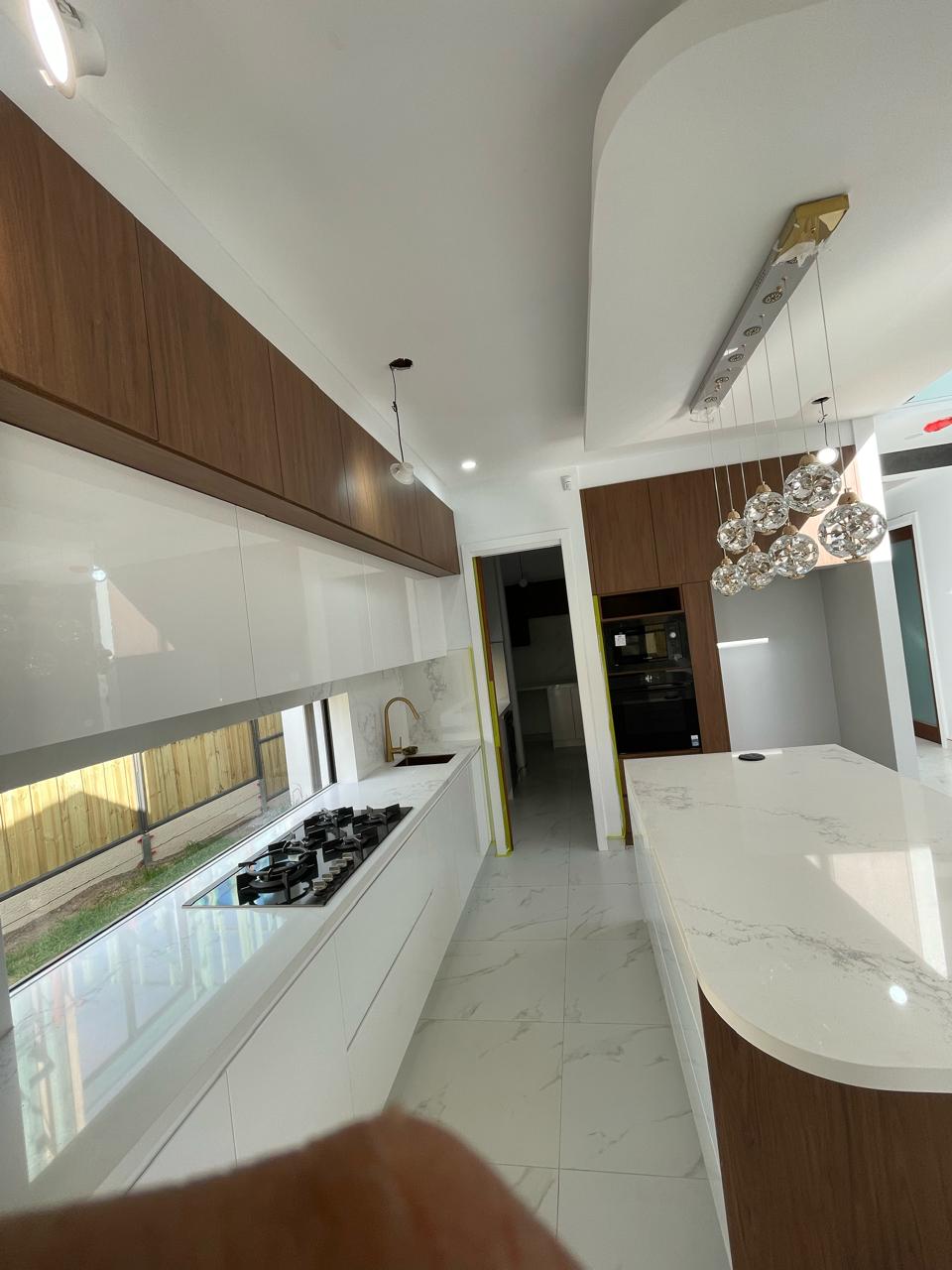 Contemporary white and timber kitchen with gas cooktop, marble-look benchtops, island and pendant lighting