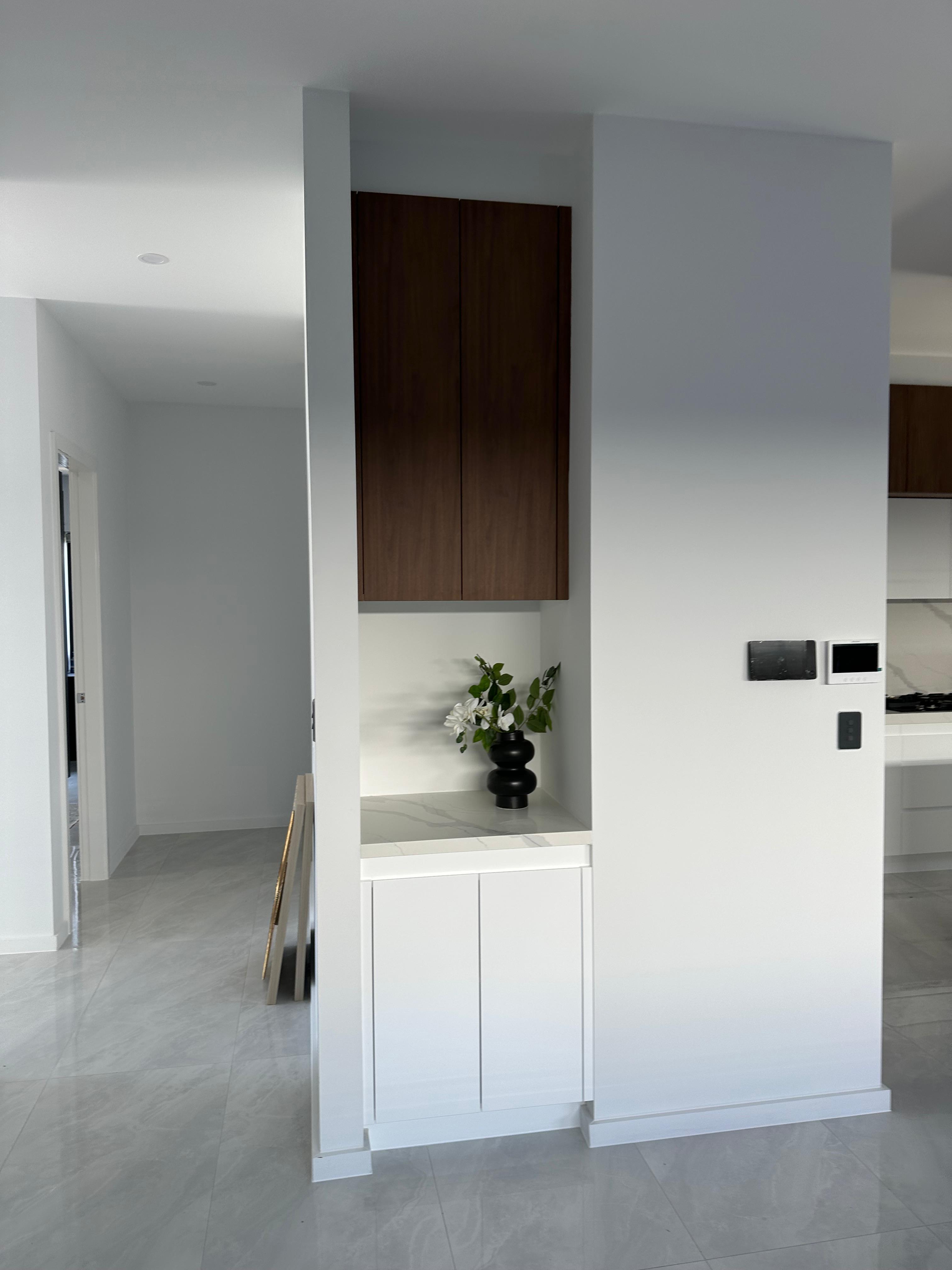 Built-in hallway storage cabinet with timber doors, white drawers, marble-look shelf and decorative vase