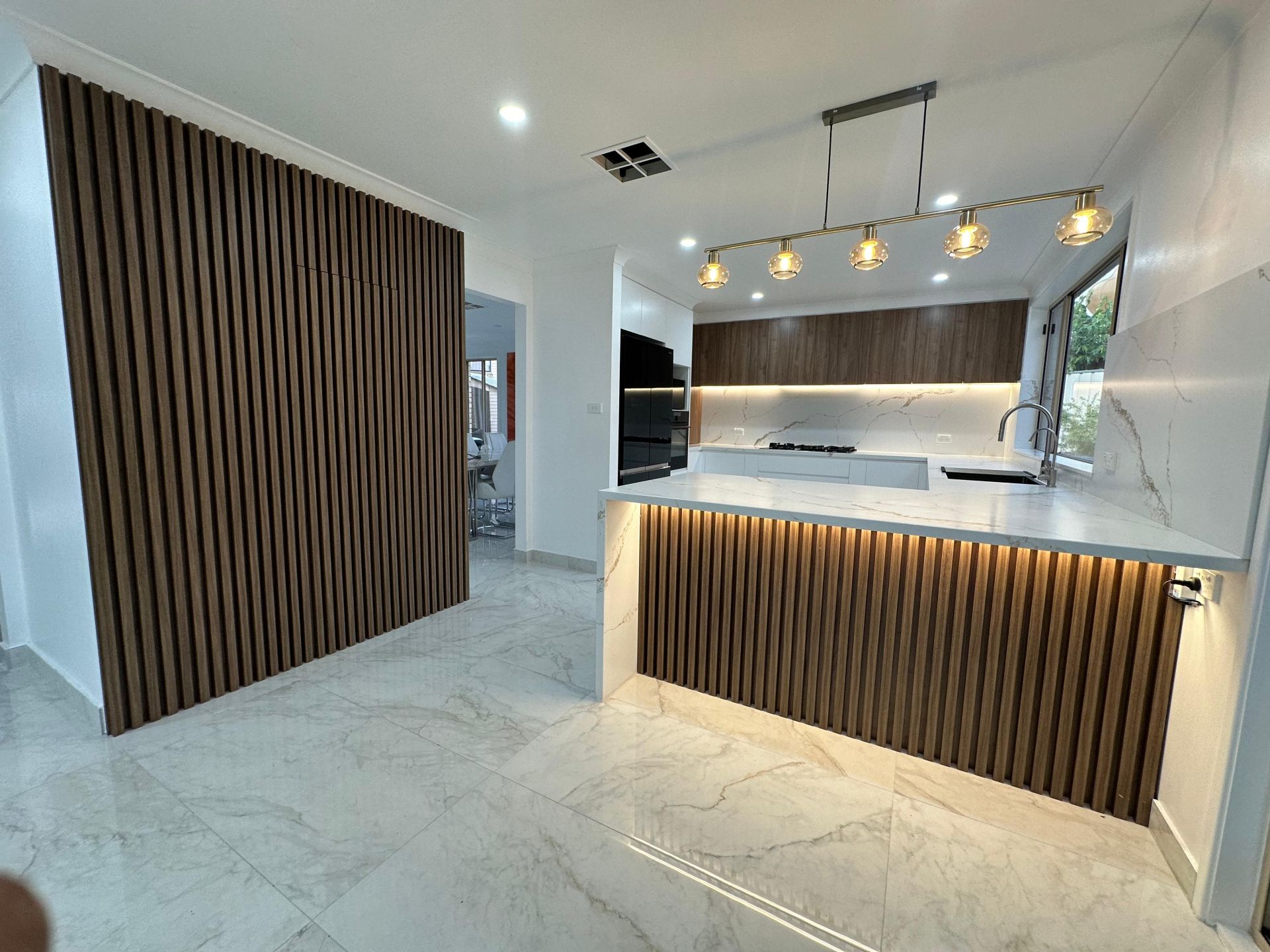 Bright kitchen with blue island cabinets, white shaker cabinetry, quartz countertop and glass pendant lights