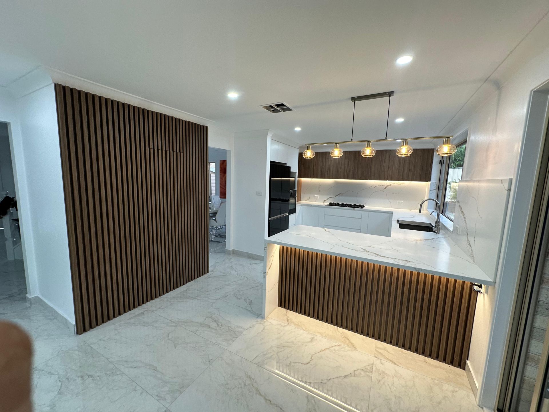 White shaker kitchen with quartz countertop, herringbone backsplash, gas cooktop and stainless steel range hood
