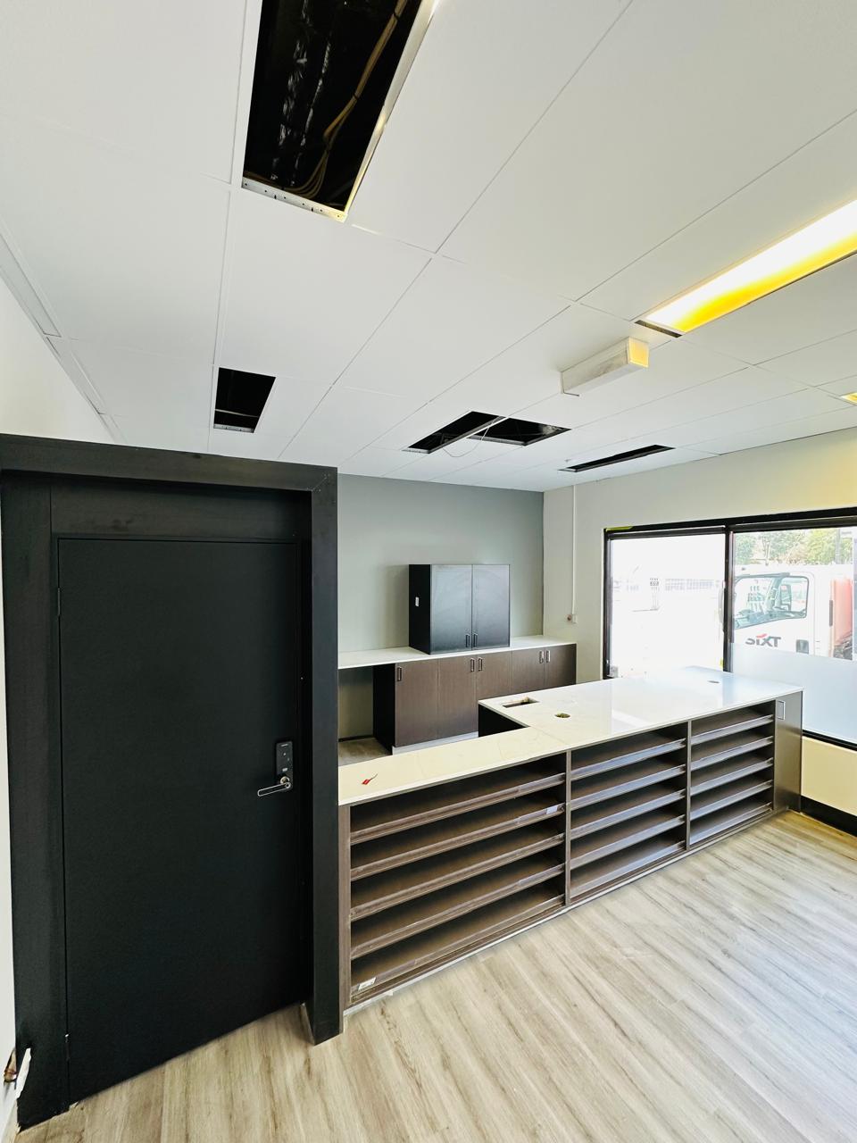 Custom office reception counter with open shelving, white benchtop and dark cabinetry