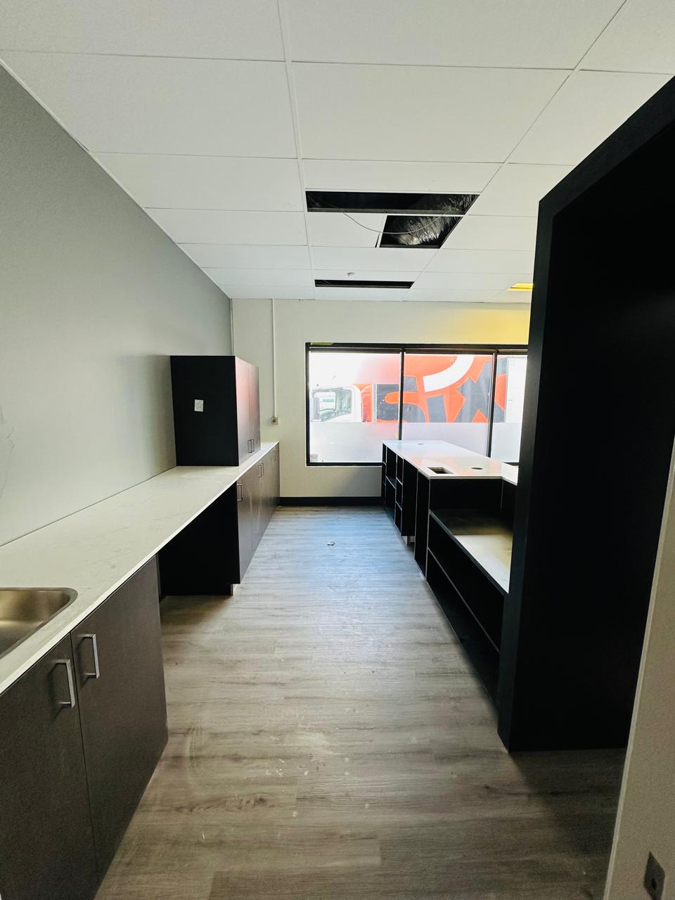 Modern office kitchenette with custom dark cabinetry, white benchtops and integrated sinks