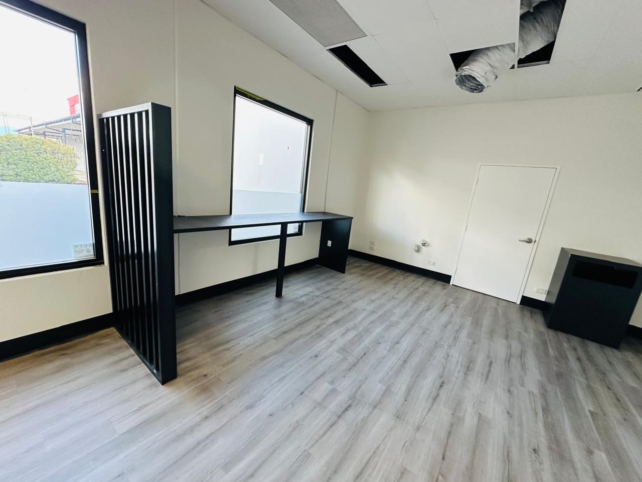 Custom black office workstation with slatted partition and grey timber flooring