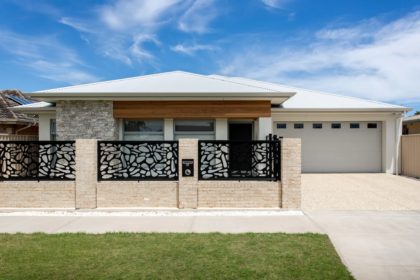 Modern home exterior with timber cladding, stone feature wall and decorative black front fence