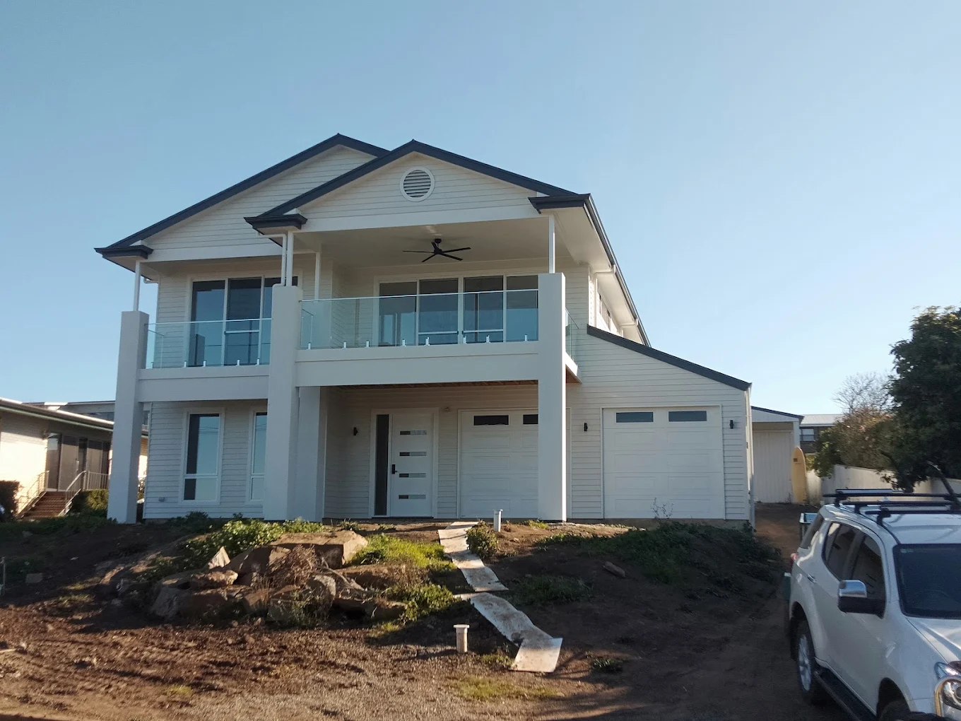 Two-storey modern home exterior with balcony, garage and white weatherboard cladding
