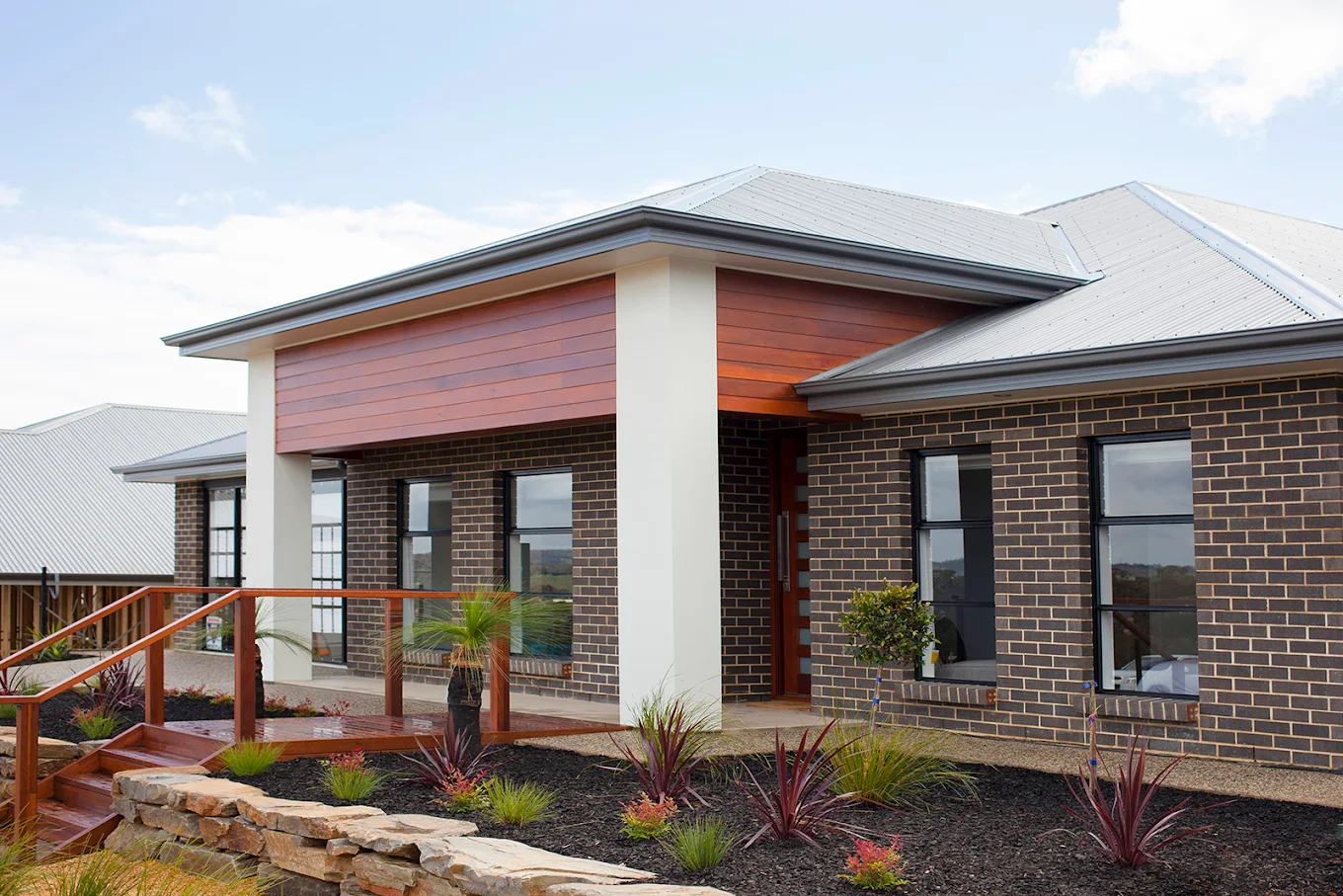 Modern brick home exterior with timber cladding, landscaped garden and timber front deck