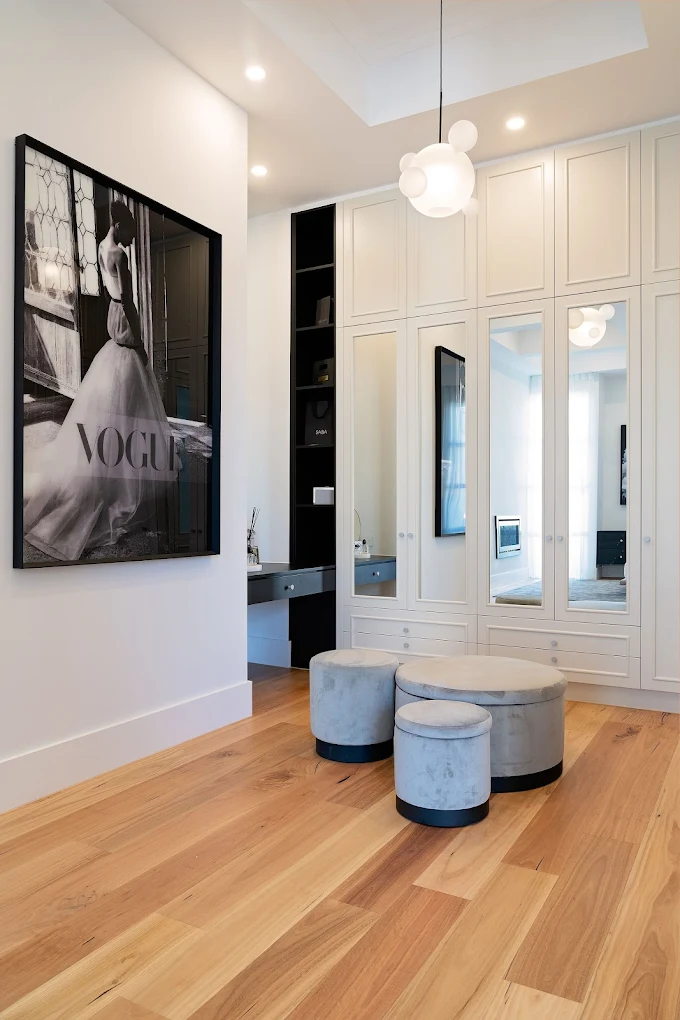 Custom white walk-in wardrobe with built-in cabinets, mirrored doors and drawer storage