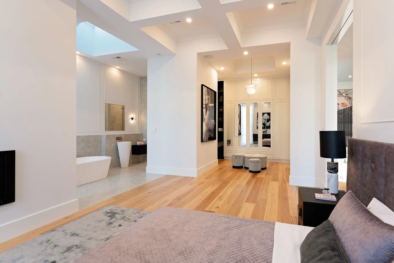 Luxury bedroom with walk-in wardrobe cabinetry, freestanding bathtub and timber flooring