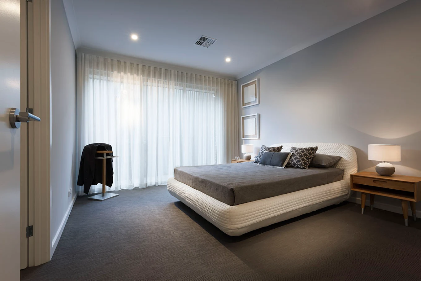 Modern bedroom with upholstered bed, wooden bedside tables, pendant lighting and sheer curtains