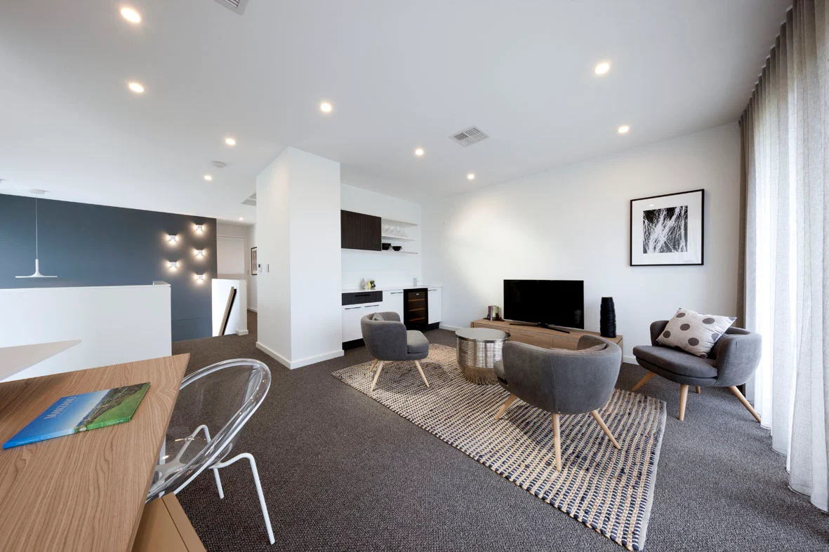 Modern living room with grey armchairs, TV unit, patterned rug and built-in cabinetry
