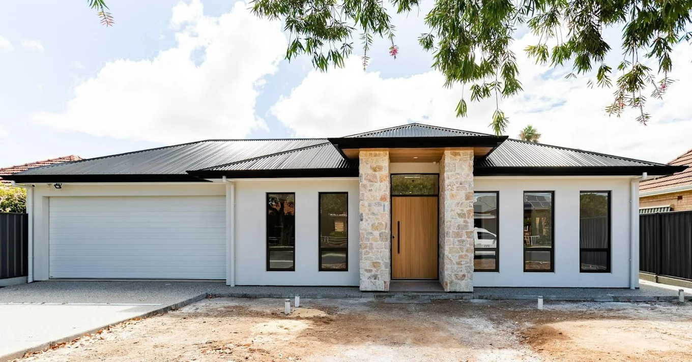 Modern single-storey home exterior with stone entrance pillars, timber front door and double garage