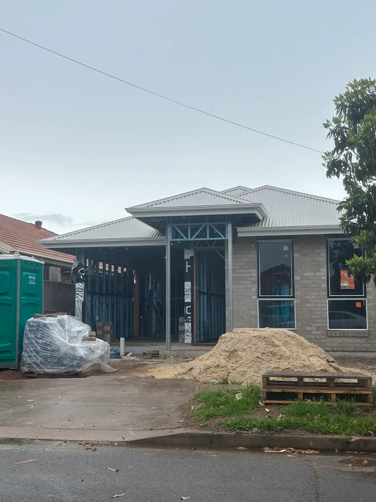 Modern brick house under construction with front entry framework and building materials
