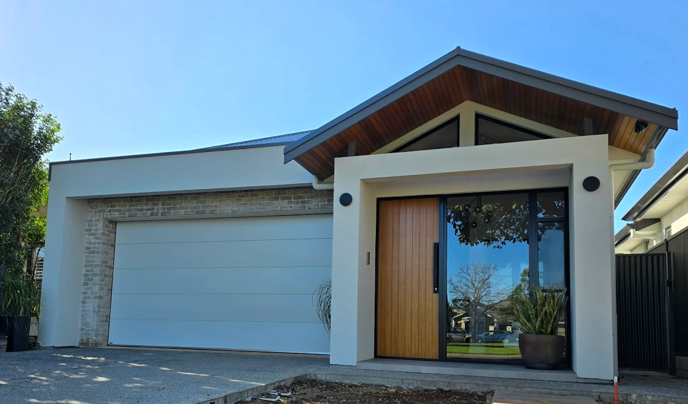 Modern home entrance with timber front door, large glass window and white double garage
