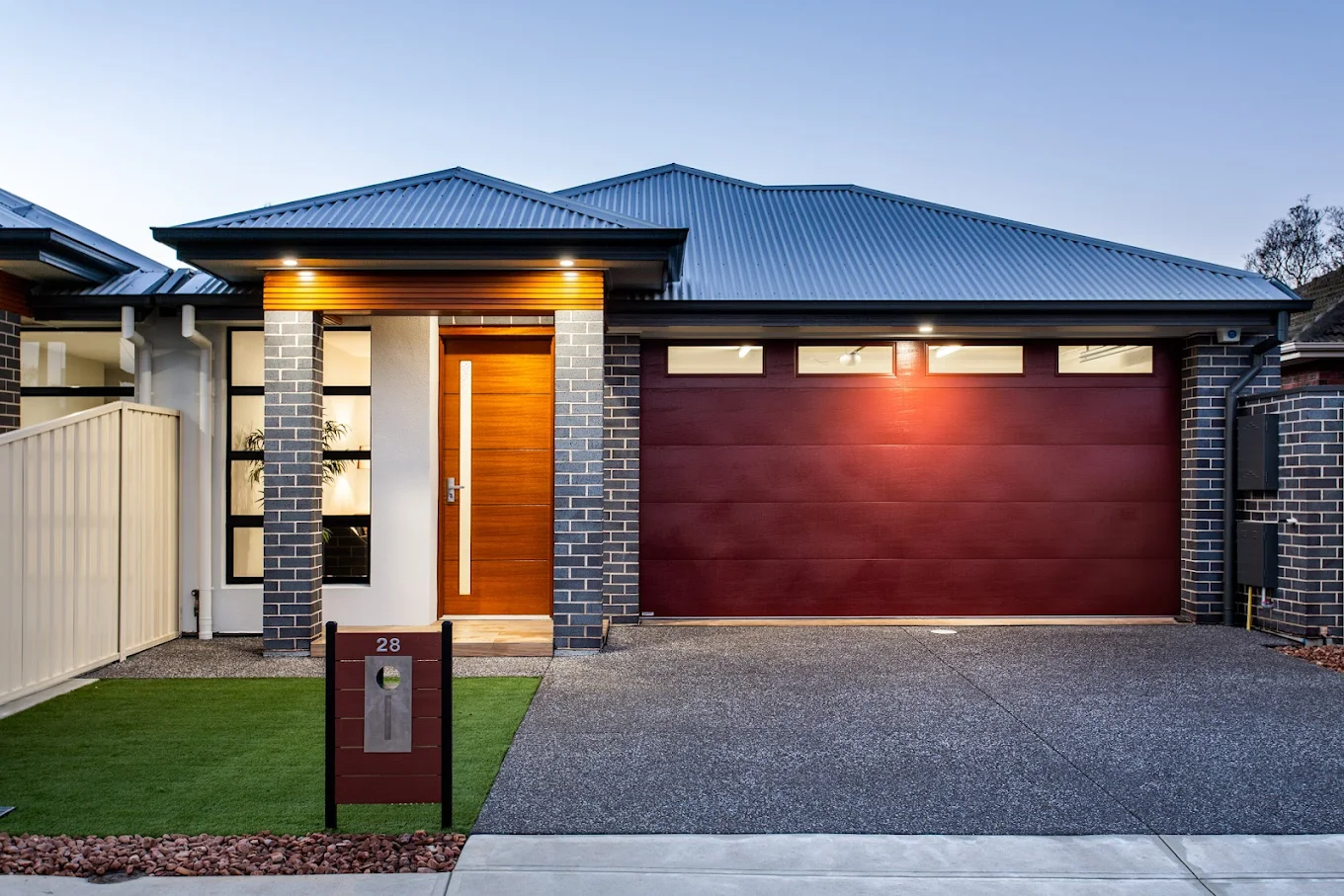 Custom timber front door and matching dark red sectional garage door on a modern brick home